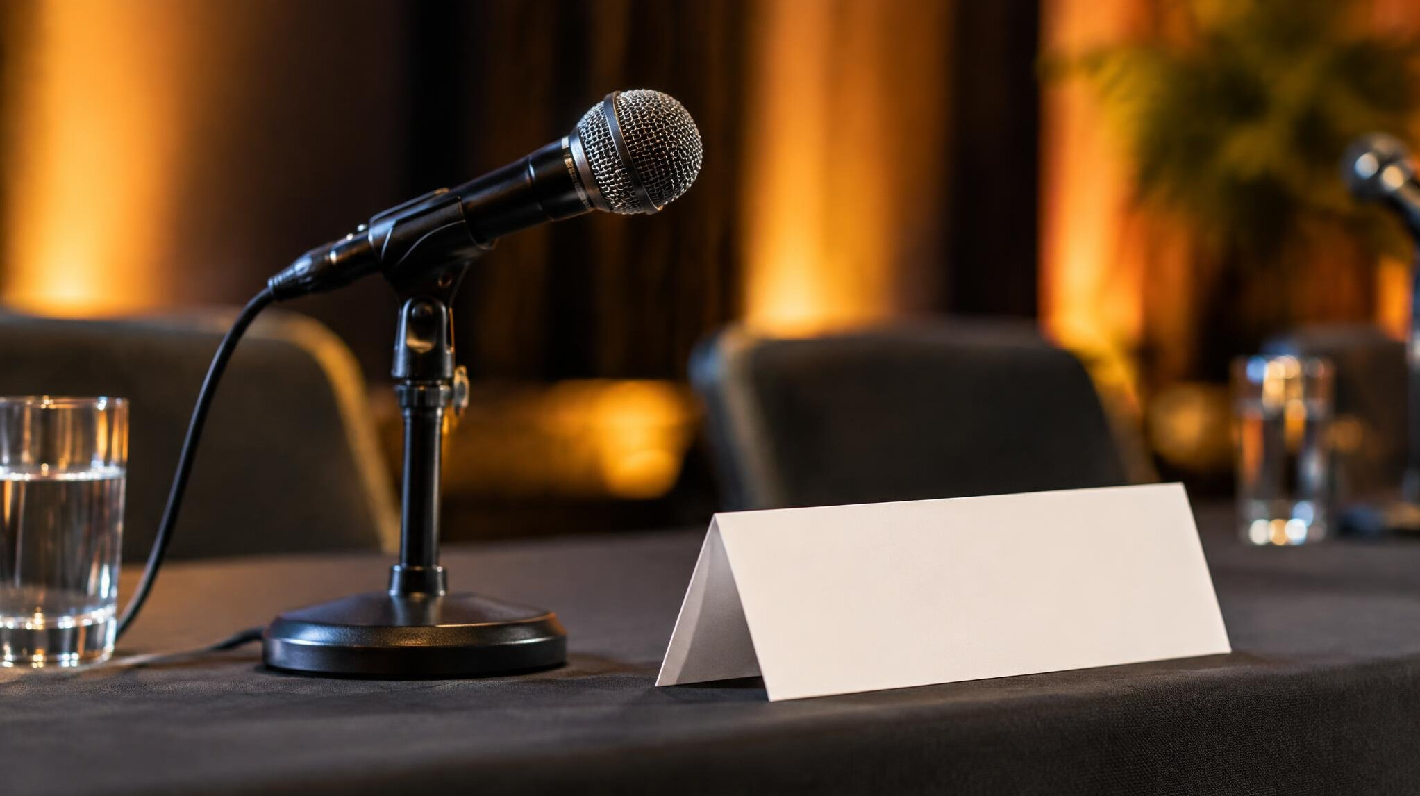 Close-up of a microphone and name placard on a panel table